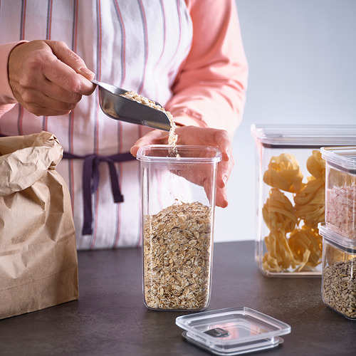 La persona vierte avena en un frasco transparente y hermético de una bolsa de papel. Tarros apilables, con botón de ventilación para facilitar la apertura.