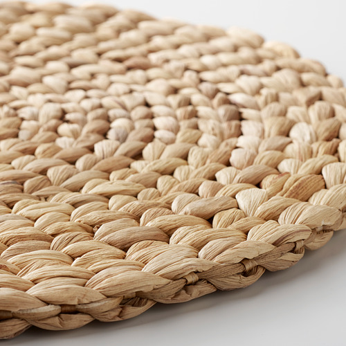 Estera de fibra natural tejida a mano, primer plano. Intrincado patrón trenzado visible, que muestra artesanía de calidad.