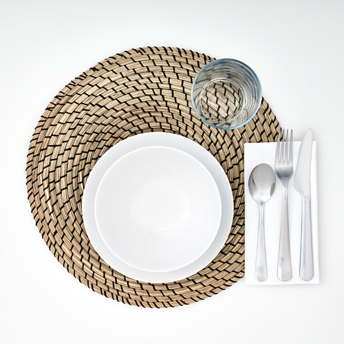 Mantel individual redondo tejido con plato blanco, vidrio y cubiertos cuidadosamente dispuestos.