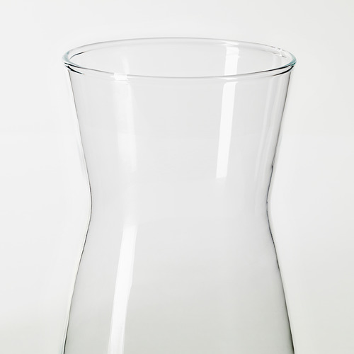 Jarra de vidrio transparente y elegante con curvas suaves, en posición vertical. Perfecto para bebidas o flores, reflejando la luz para una apariencia nítida.