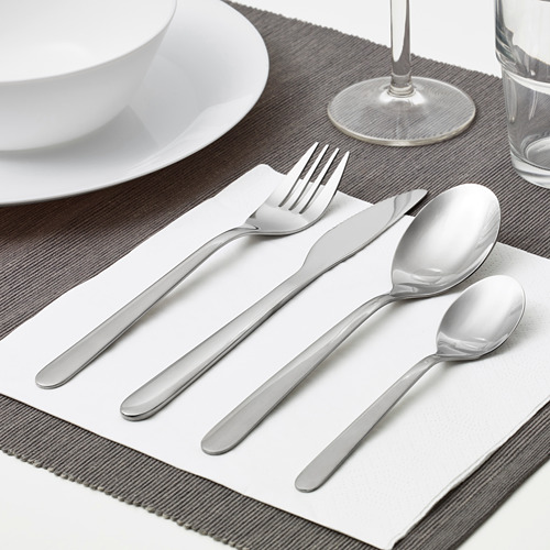 Juego de cubiertos colocado sobre tela: tenedor, cuchillo, cuchara, cucharilla, listo para usar.
