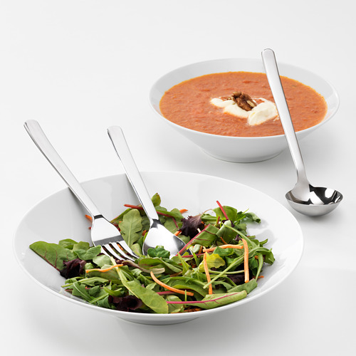 Dos cuencos de comida con utensilios metálicos para servir. Uno tiene ensalada, el otro sopa cremosa.