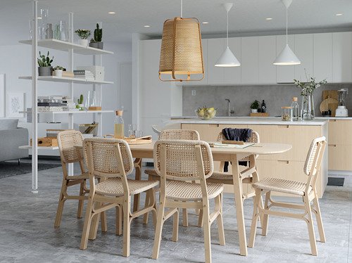 Cocina luminosa y minimalista, un juego de comedor de madera clara con sillas tejidas, lámparas de mimbre colgantes y lámparas colgantes blancas.