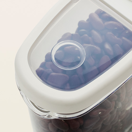 Frasco transparente con tapa blanca, que muestra los caramelos morados almacenados. Diseño transparente para una fácil visualización.