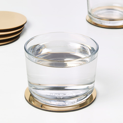 Vaso con agua en un posavasos metálico.