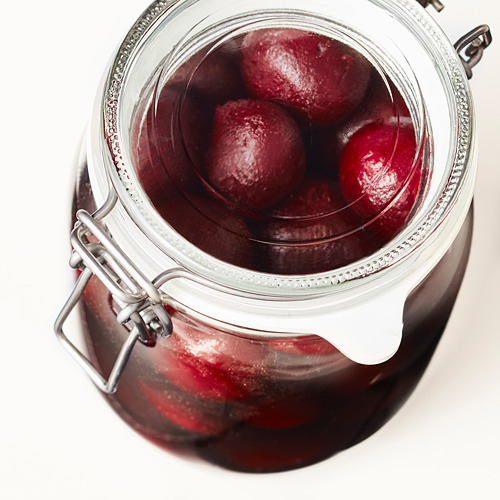 El frasco de vidrio transparente con abrazaderas de metal contiene remolacha en escabeche de color rojo púrpura. El cierre hermético conserva sabores y aromas.