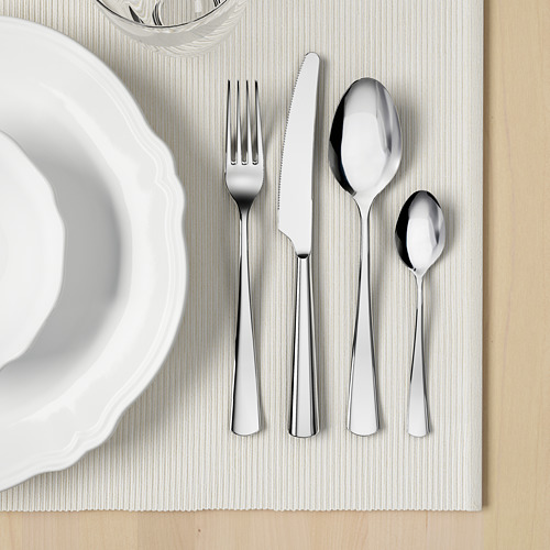 Un conjunto de cubiertos pulidos cuidadosamente dispuestos en un mantel individual, que incluye tenedor, cuchillo, cuchara y cucharadita, ideal para cenar.