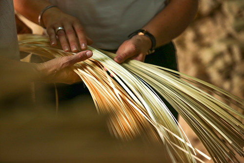 La persona teje a mano una cesta de bambú natural, mostrando artesanía y diseño tradicional.
