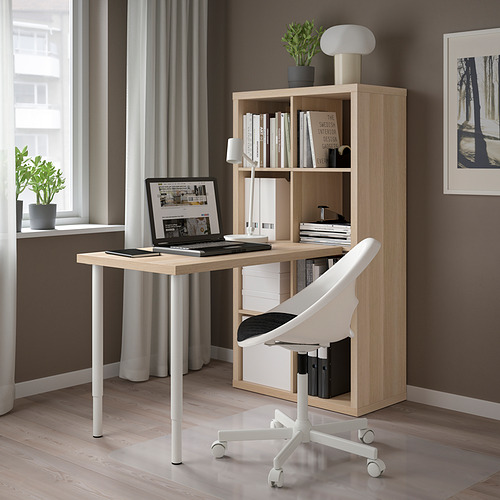Moderna oficina en casa con escritorio y estantería KALLAX de madera clara. Silla blanca, lámpara y computadora portátil. Paredes grises y gran ventanal.