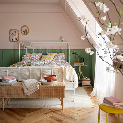 Dormitorio con paredes rosas, cabecero verde y ropa de cama floral colorida DAGGSALVIA . Banco tejido, libros, flores.