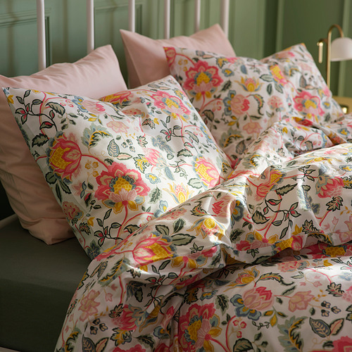 Cama con edredón floral colorido y almohadas rosas. Ropa de cama brillante, suave y acogedora.