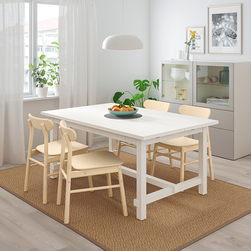 Moderno juego de comedor con mesa extensible, sillas, frutero y grandes ventanales.