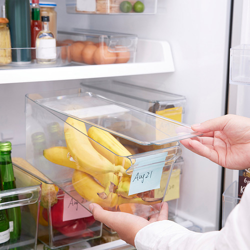 Persona que sostiene una caja de plátano etiquetada con tapa y asa para el almacenamiento de alimentos.