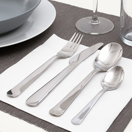 Cubiertos pulidos colocados en servilleta, que incluyen tenedor, cuchillo y cucharas, listos para comer.