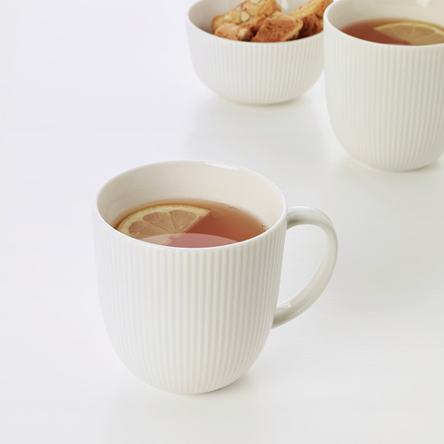Tres tazas blancas con té de limón; El primer plano de una taza muestra una rodaja de limón, lo que sugiere un sabor refrescante. Diseño simplista y elegante.