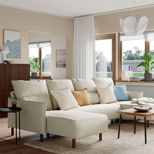 Salón moderno con sofá MANNARP crema, ventanas, mesas auxiliares y plantas.