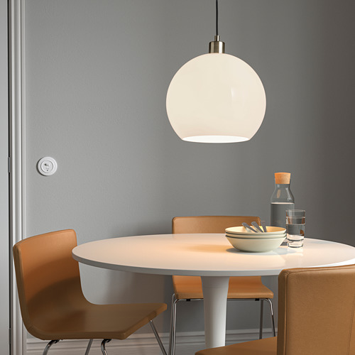 Moderno comedor con luz SOLHETA, sillas naranjas, tazón, vasos y botella.