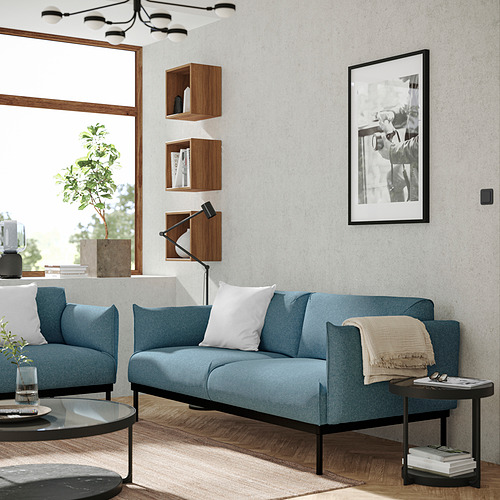 Sala de estar moderna con sofá azul, estantes, mesa negra, planta y cuadro.