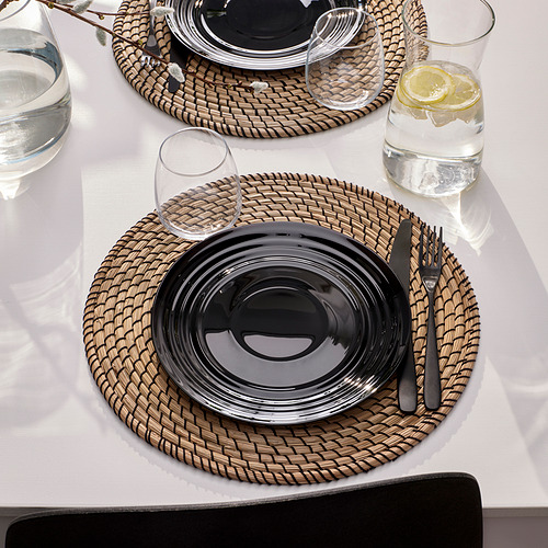 Mesa decorada con cristalería NÄTBARB, con platos circulares brillantes y tazas de cristal a juego con rodajas de limón sobre un mantel blanco, listo para comer.