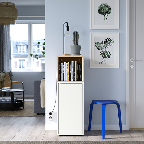 Sala de estar moderna con gabinete EKET, libros, cactus, taburete azul, estampados y asientos acogedores.