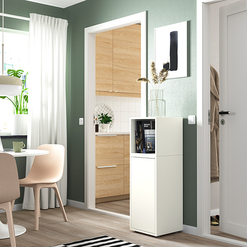 Pequeño mueble EKET blanco, puerta de cristal, entre la cocina y la zona de comedor. Estanterías visibles en el interior.