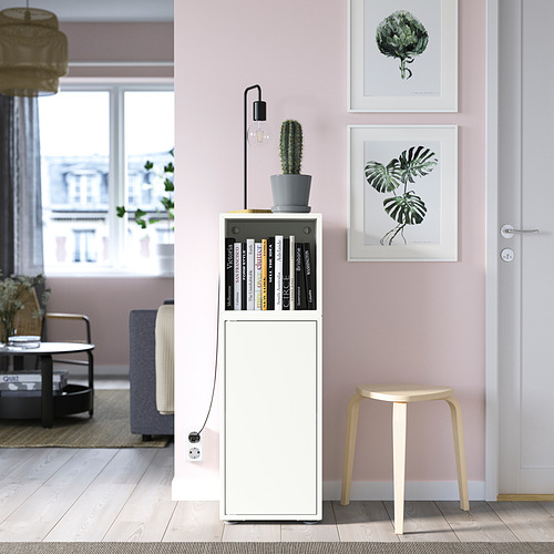 Mueble EKET blanco, lámpara negra, planta, cuadros de pared rosas, taburete, salón.
