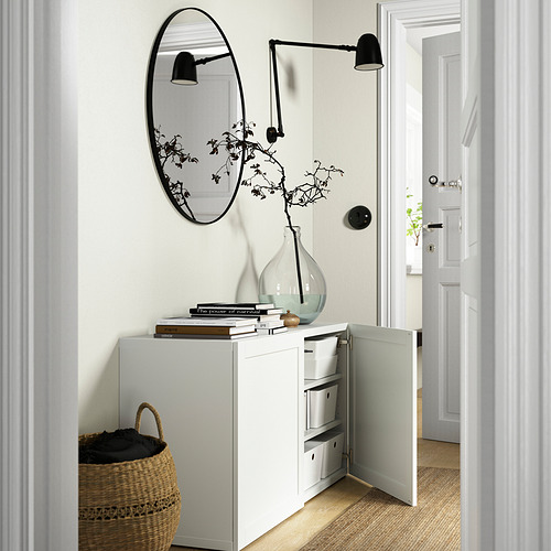 Aparador BESTÅ con puerta abierta, espejos, plantas, lámparas, cesta de tela.