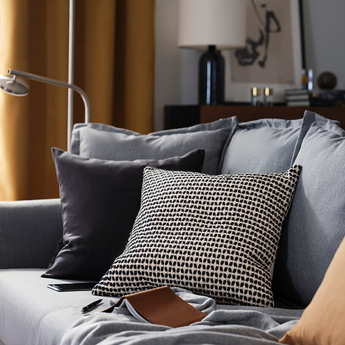 Moderno salón gris con cojines; uno con patrón en blanco y negro, textura suave y cremallera.