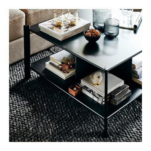 Estante JÄTTESTA negro de 3 niveles, que exhibe libros, decoración y tazón con bocadillos y velas. Elegantes patas de metal, estantes de bambú. Diseño moderno y funcional.