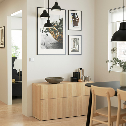 Moderno salón con aparador BESTÅ, fotos, lámparas colgantes y silla de madera. Luminoso y acogedor.