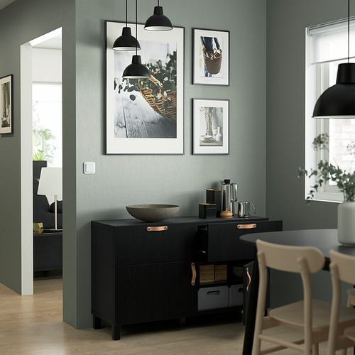Cocina moderna, un aparador BESTÅ con estantes ajustables, cajones de cierre suave y amplio espacio de almacenamiento. Sobre ella, tres fotos enmarcadas cuelgan de una pared verde.