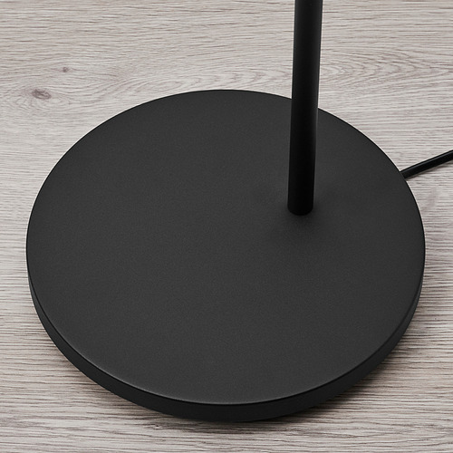 Base de lámpara de pie negra sobre suelo de madera, diseño elegante, base redonda robusta con poste de soporte central, acabado de calidad.