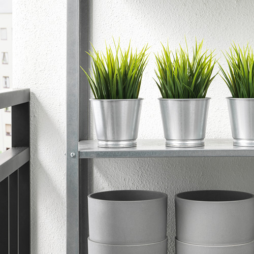 Estantería con tres macetas de plata que contienen plantas verdes, protegidas con protectores de suelo.