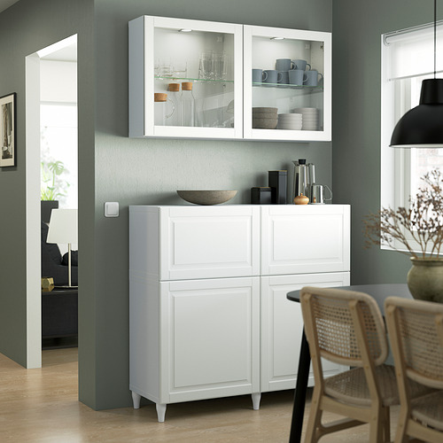 Mueble blanco OSTVIK con puertas de cristal, detalles tallados, encaja perfectamente en la zona del comedor, más pequeño que la silla de mimbre.