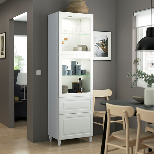 Mueble de almacenaje alto BESTÅ con puertas y cajones de cristal, que muestra el menaje de cocina.
