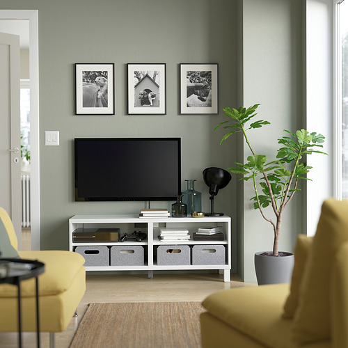 Sala de estar moderna con mueble de tv BESTÅ, fotos, plantas, sillas amarillas, cajas de almacenamiento y decoración.