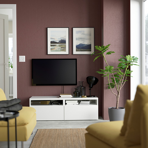 Sala de estar moderna con mueble de tv BESTÅ, estantes, cajones, TV de pantalla plana, sillas amarillas, planta verde, fotos de montaña en pared morada.