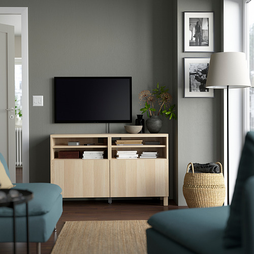 Sala de estar moderna con paredes grises, con un banco de televisión BESTÅ, un televisor grande, sillas azules y una alfombra acogedora.