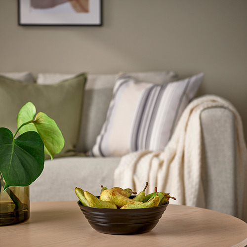 Cuenco giratorio de vidrio, NÄTBARB, sobre la mesa cerca de la planta verde, sofá gris con almohadas a rayas.