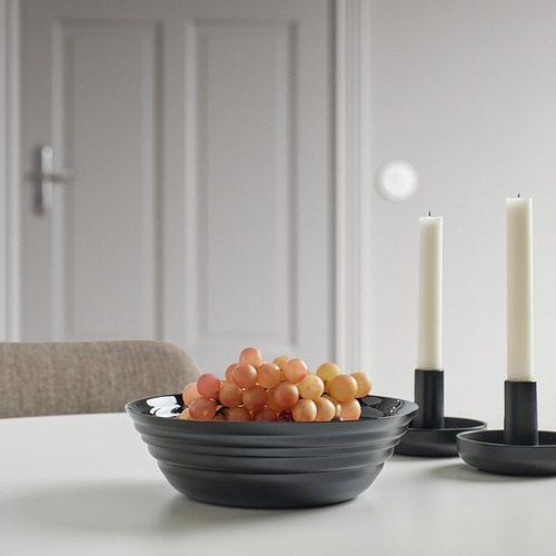 Cuenco de NÄTBARB negro con uvas sobre mesa blanca, candelabros.