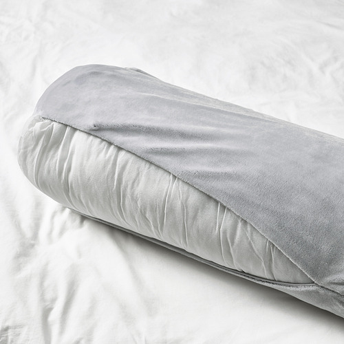 Un cojín suave y cilíndrico sobre una cama. Es versátil para soportar varias partes del cuerpo, perfecto para niños a partir de los 3 años.