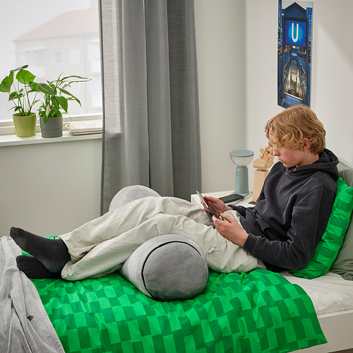 Adolescente con teléfono en almohada verde para el cuerpo, planta junto a la ventana, cartel u.