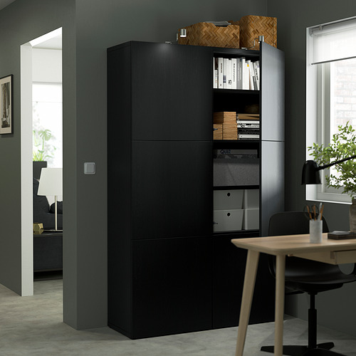 Moderna configuración de oficina en casa con armario de almacenamiento BESTÅ negro con estantes ajustables, libros y un escritorio de madera con una silla.