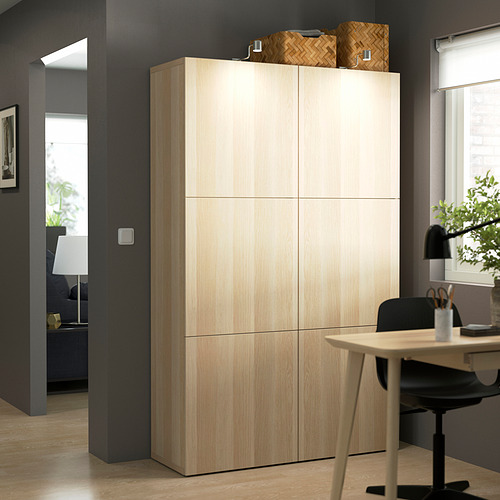 Gran armario de madera BESTÅ con seis puertas, más alto que el escritorio y la lámpara, dos cestas en la parte superior.