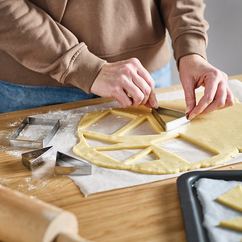 La persona usa cortadores de galletas en la masa. Los cortadores crean formas, ideales para hornear y decorar.