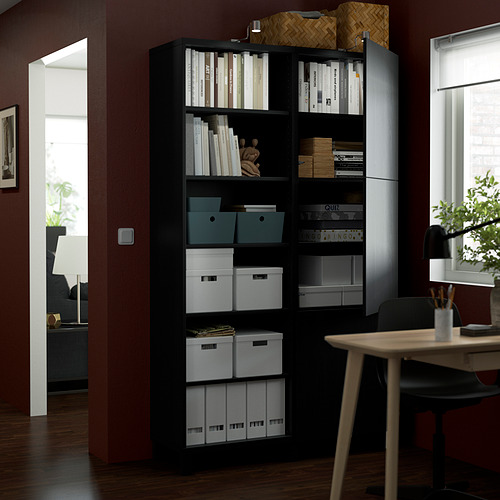 Un mueble de almacenamiento BESTÅ negro sostiene libros y cajas en estanterías, con un mecanismo de apertura a presión. Los estantes y bisagras ajustables optimizan el almacenamiento.