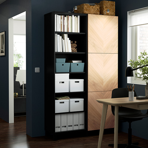 Black BESTÅ storage unit with open shelves and closed cabinets, organized boxes against dark blue wall.