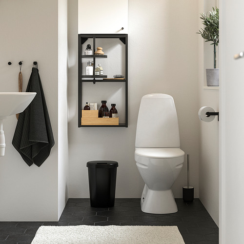 Baño moderno: paredes blancas, azulejos oscuros, inodoro, papelera, cepillo, toalla, estantería, planta.