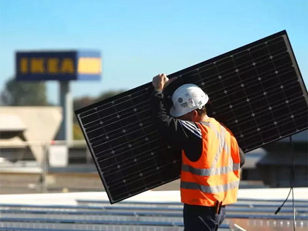 Technician installing a solar panel in front of an IKEA store sign.