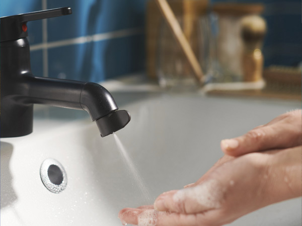 Hands washing under a stream of water from a matte black faucet.